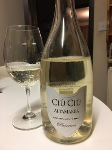 An open bottle of Ciu Ciu Brut Passerina Alta Marea with a partially filled glass to the left