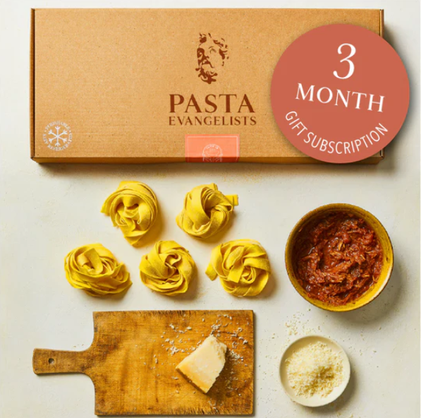 Image of the pasta subscription box with pasta ribbons in circles, some sauce in a bowl and grated cheese in a bowl.